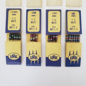 May include: Four vintage electronic resistors in yellow and blue packaging. Each package displays resistance values, wattage, and the "IRC" logo. The resistors have color-coded bands, indicating their values. The text on the packages includes "1.0 MEG", "270K", "1000", and "68K".