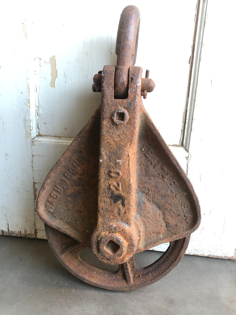 May include: A rusty cast iron pulley with a large wheel and a hook on top. The pulley is labeled "Wash Iron 200"