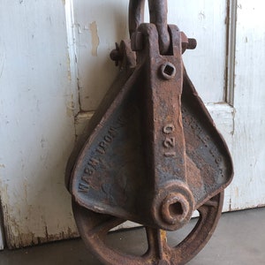 May include: A rusty cast iron pulley with a yellow painted wheel and the text "WASH IRON CO. 120" on the side.