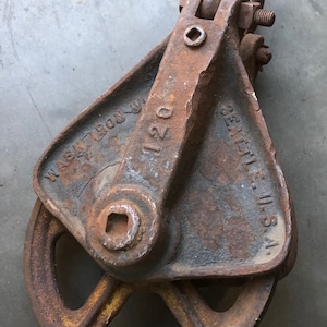 May include: A rusty cast iron pulley with a 120 stamped on the side. The pulley is labeled "Eagle, U.S.A." and "Wash. Iron Wks."