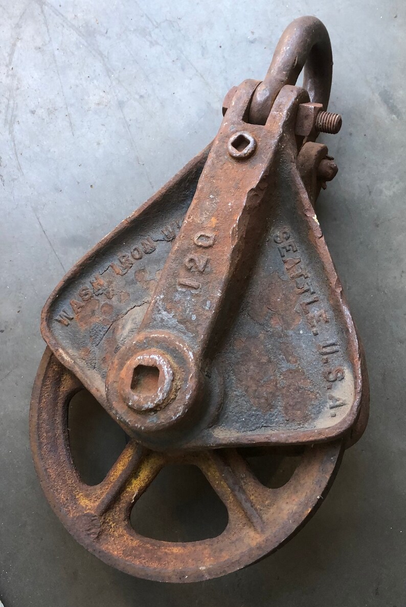 May include: A rusty cast iron pulley with a 120 stamped on the side. The pulley is labeled "Eagle, U.S.A." and "Wash. Iron Wks."