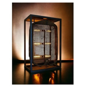 May include: A vintage car radiator grill is encased in a black metal frame and illuminated with warm white lights. The grill is made of metal and has a rusty patina. The frame is made of wood and has a dark stain.