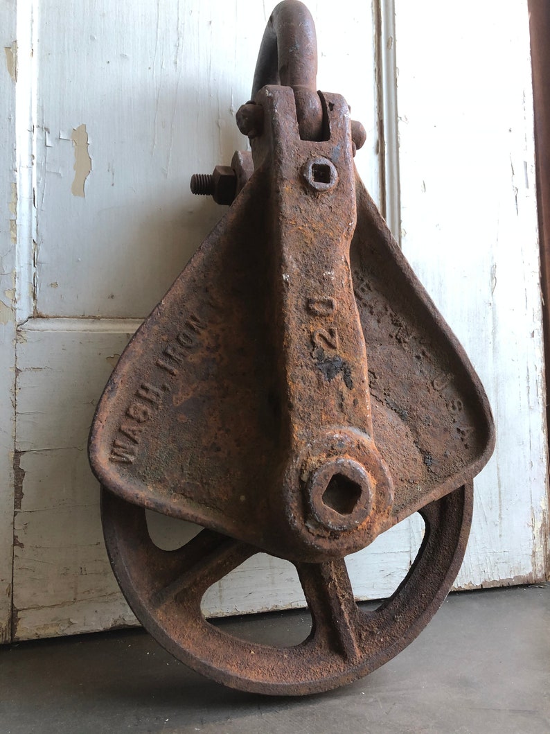 May include: A rusty cast iron pulley with a wheel and a hook. The pulley is labeled "WASH. IRON" and "220".