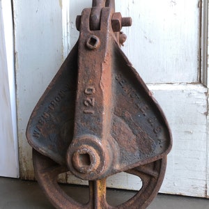 May include: A rusty iron pulley with a wheel and a hook. The pulley is labeled "120" and "WARREN IRON WKS."