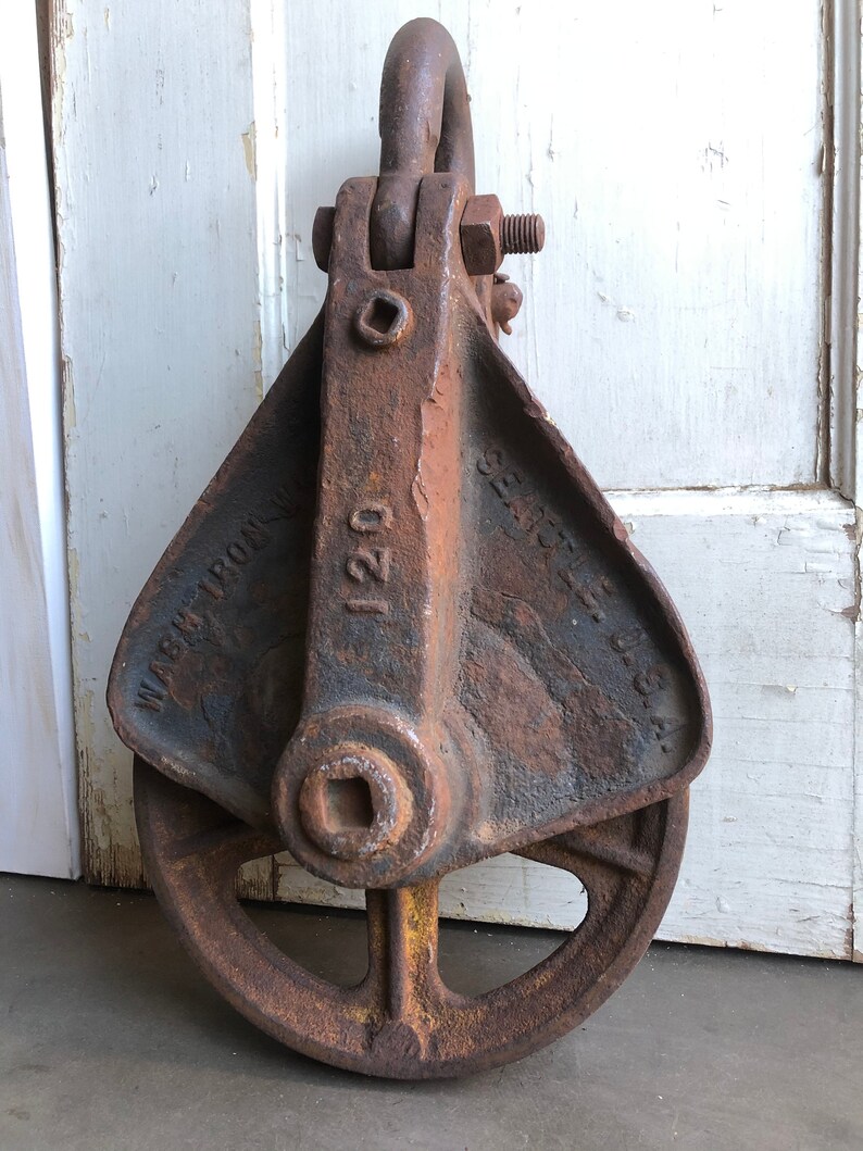 May include: A rusty iron pulley with a wheel and a hook. The pulley is labeled "120" and "WARREN IRON WKS."