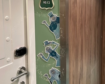 May include: A green sign with the number 9512 and a gold emblem featuring an owl. The sign has three cartoon ghost figures. The door is white with a silver handle and a black card reader.