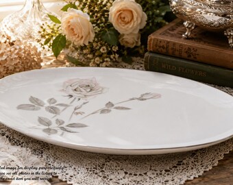 May include: An oval white porcelain serving platter featuring a delicate illustration of a single blooming rose and a rosebud with grey-toned leaves and stems. The platter has a smooth, glossy finish and a simple, clean edge design.