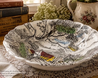 May include: A white ceramic bowl with a scalloped edge featuring a detailed black and white transferware landscape scene. The illustration depicts a house with a red roof, trees, and foliage with subtle accents of green, yellow, and blue paint.
