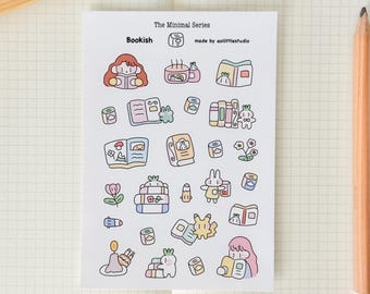 Puede incluir: Una hoja de pegatinas con una variedad de ilustraciones, incluyendo una niña leyendo un libro, una pila de libros, un conejito y una taza de té. Las pegatinas son de estilo minimalista y están etiquetadas como "The Minimal Series" y "Bookish".