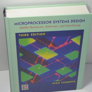 May include: A green and white book titled "Microprocessor Systems Design 68000 Hardware, Software, and Interfacing" with the words "Third Edition" and "Alan Clements" on the cover. The cover features a colourful abstract design of squares and lines.