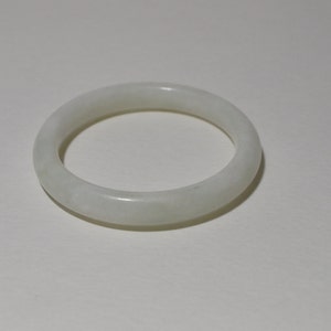 May include: A white jade bangle bracelet. The bangle is smooth and polished.
