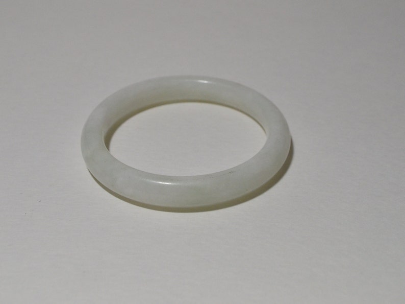 May include: A white jade bangle bracelet. The bangle is smooth and polished.