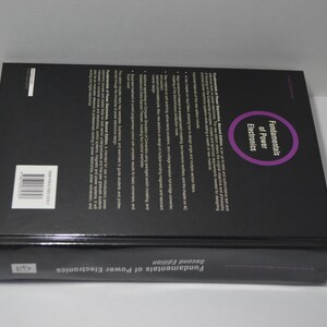 May include: The back cover of a black book titled "Fundamentals of Power Electronics" with the second edition printed on the bottom. The book has a purple circle with the text "Fundamentals of Power Electronics" inside.