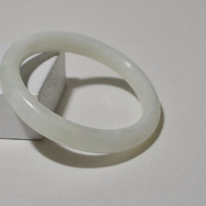 May include: A white jade bangle bracelet. The bangle is smooth and polished.