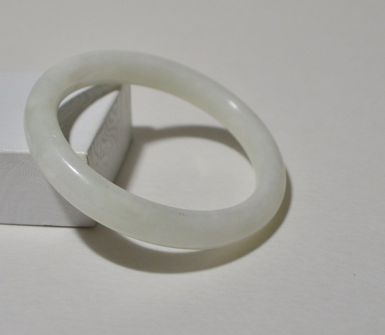 May include: A white jade bangle bracelet. The bangle is smooth and polished.