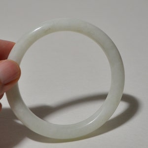May include: A white jade bangle bracelet. The bangle is smooth and polished.