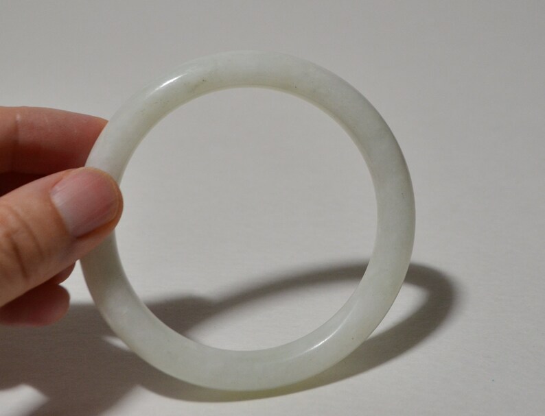 May include: A white jade bangle bracelet. The bangle is smooth and polished.