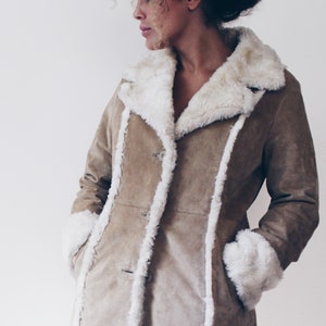 May include: A brown suede jacket with a white faux fur collar and cuffs. The jacket has a button closure and two pockets.