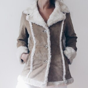 May include: A brown suede jacket with a white faux fur collar and trim. The jacket has a button closure and pockets.