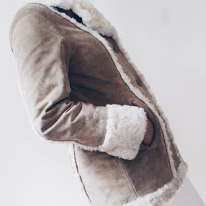 May include: A brown suede jacket with a white faux fur collar and cuffs. The jacket has a button closure and pockets.