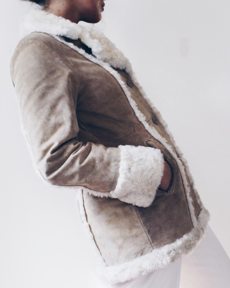 May include: A brown suede jacket with a white faux fur collar and cuffs. The jacket has a button closure and pockets.