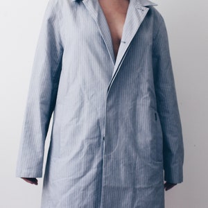 May include: A long, light blue striped jacket with a button closure and a single pocket on the left side.