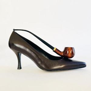 May include: A white ceramic mug with a black handle and the text "But First, Coffee" in a black, bold font. The mug is on a wooden surface.