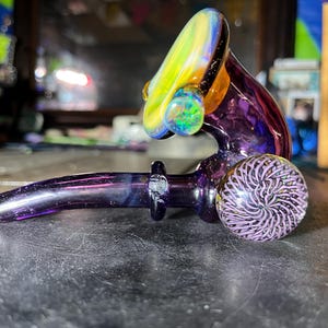 Op de afbeelding: Een witte keramische mok met een zwarte handgreep en de tekst "But First, Coffee" in een zwarte, vette letter. De mok staat op een wit oppervlak.