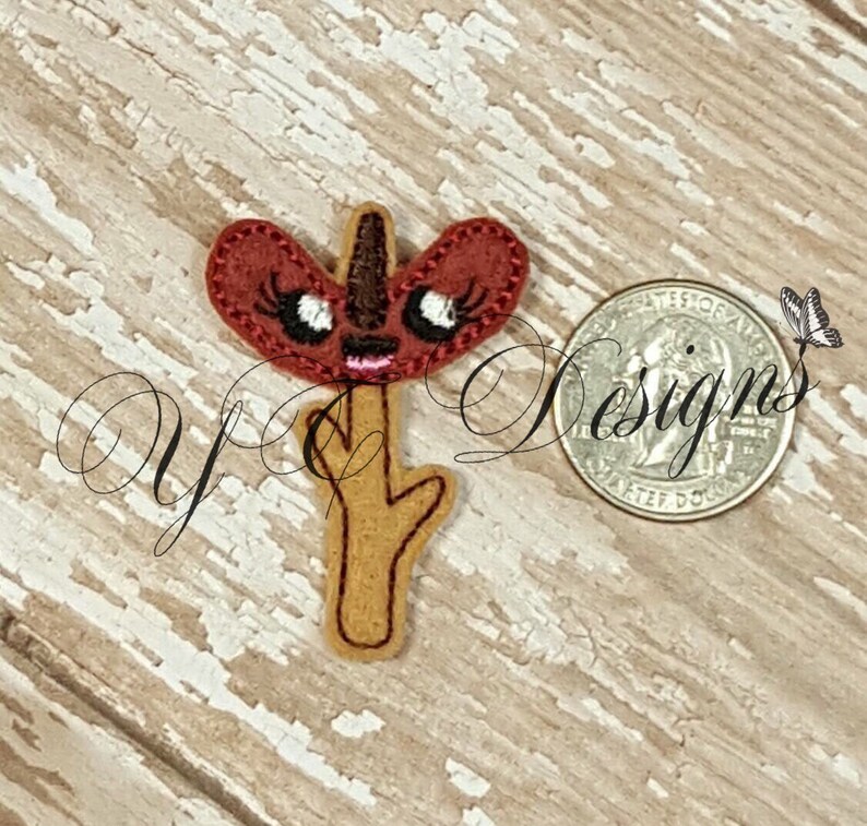 Op de afbeelding: Een vilt applique van een rode en bruine cartoon bloem met een grillig gezicht en wimpers. De bloem zit op een bruine stok.