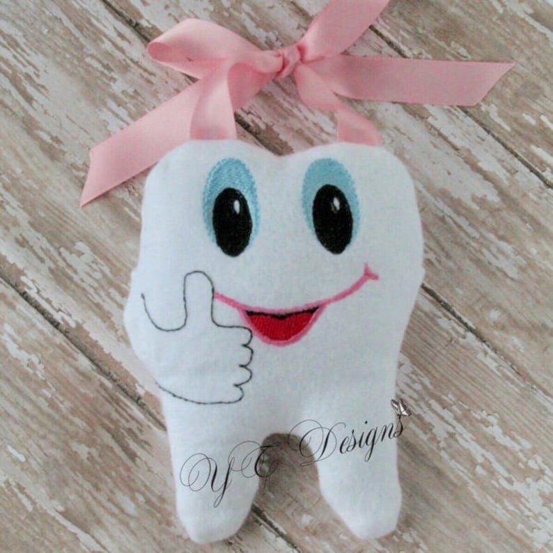 May include: A white plush tooth with a smiling face and a thumbs up gesture. The tooth has blue eyes, a pink mouth, and a pink ribbon attached to the top.