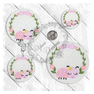 May include: Three embroidered felt circles featuring a ladybug design. Each circle has a green leafy wreath with pink flowers and a pink bow. The largest circle depicts a ladybug with closed eyes and a yellow flower on its head. The medium circle shows a ladybug with closed eyes and a yellow flower on its head. The smallest circle displays a ladybug with closed eyes and a yellow flower on its head.