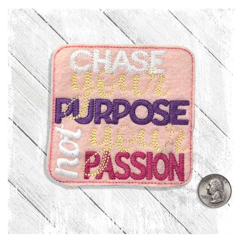 May include: Pink felt patch with white, yellow, purple, and pink embroidery. The text reads "Chase your purpose not your passion."