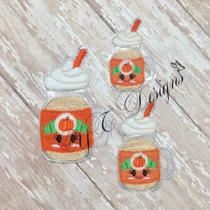 May include: Three embroidered patches of pumpkin spice mason jars with whipped cream and a straw. Each jar has a cute cartoon face with eyelashes and a pumpkin on the label.