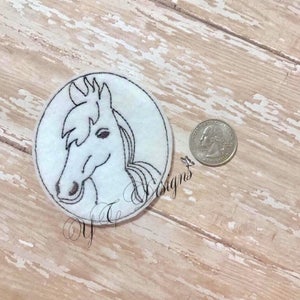 Puede incluir: Un dibujo en blanco y negro de la cabeza de un caballo, bordado en un parche circular blanco.