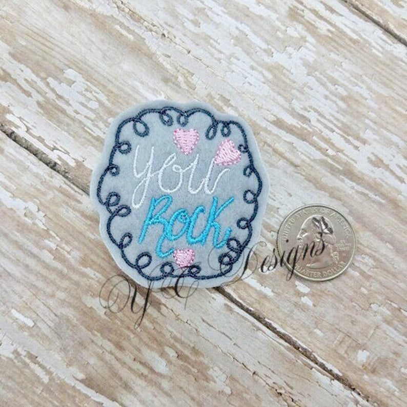 May include: Embroidered patch with a blue and white swirl design. The text "You Rock" is written in white with pink hearts.