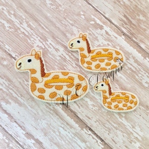 Puede incluir: Tres parches de fieltro de un flotador de piscina de jirafa. Los parches son de diferentes tamaños y todos son blancos con manchas marrones y una franja amarilla.
