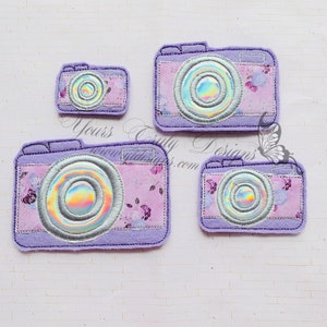 May include: Four purple felt camera patches with a holographic lens. The largest camera patch has a floral pattern. The patches are perfect for adding a touch of whimsy to your crafts.