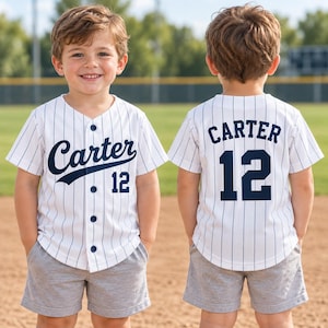 Può includere: Una maglia da baseball bianca con sottili gessature blu navy, caratterizzata dal nome Carter e dal numero 12 in caratteri blu navy sul davanti e sul retro. La maglia presenta un'abbottonatura frontale ed è abbinata a pantaloncini grigi.