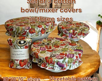 May include: Set of three cotton bowl/mixer covers in three sizes, featuring a vegetable pattern. The covers are sized at 10", 8", and 6" and are washable. The covers are on a wooden table.