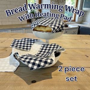 May include: A two-piece bread warming set with a heating pad. The set includes a white serving dish with a black and white checkered wrap. The text "Bread Warming Wrap With Heating Pad" is displayed at the top of the image.