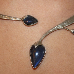 May include: A silver necklace with a delicate branch design and two dark blue gemstone accents.