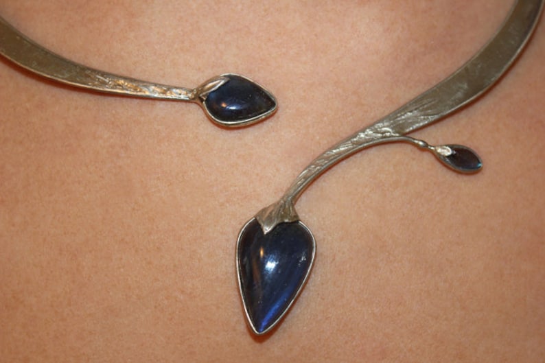 May include: A silver necklace with a delicate branch design and two dark blue gemstone accents.