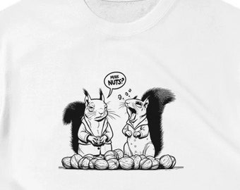 May include: White t-shirt featuring a black and white cartoon illustration of two squirrels. One squirrel is asking "MORE NUTS?" while the other squirrel is holding nuts. The shirt is a classic crew neck style.