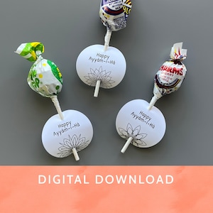 Op de afbeelding: Vier lolly's met witte papieren labels met de tekst "Happy Ayyám-i-Há" en een bloemenontwerp. De lolly's zitten in kleurrijke wikkels. De tekst "DIGITAL DOWNLOAD" staat onderaan.
