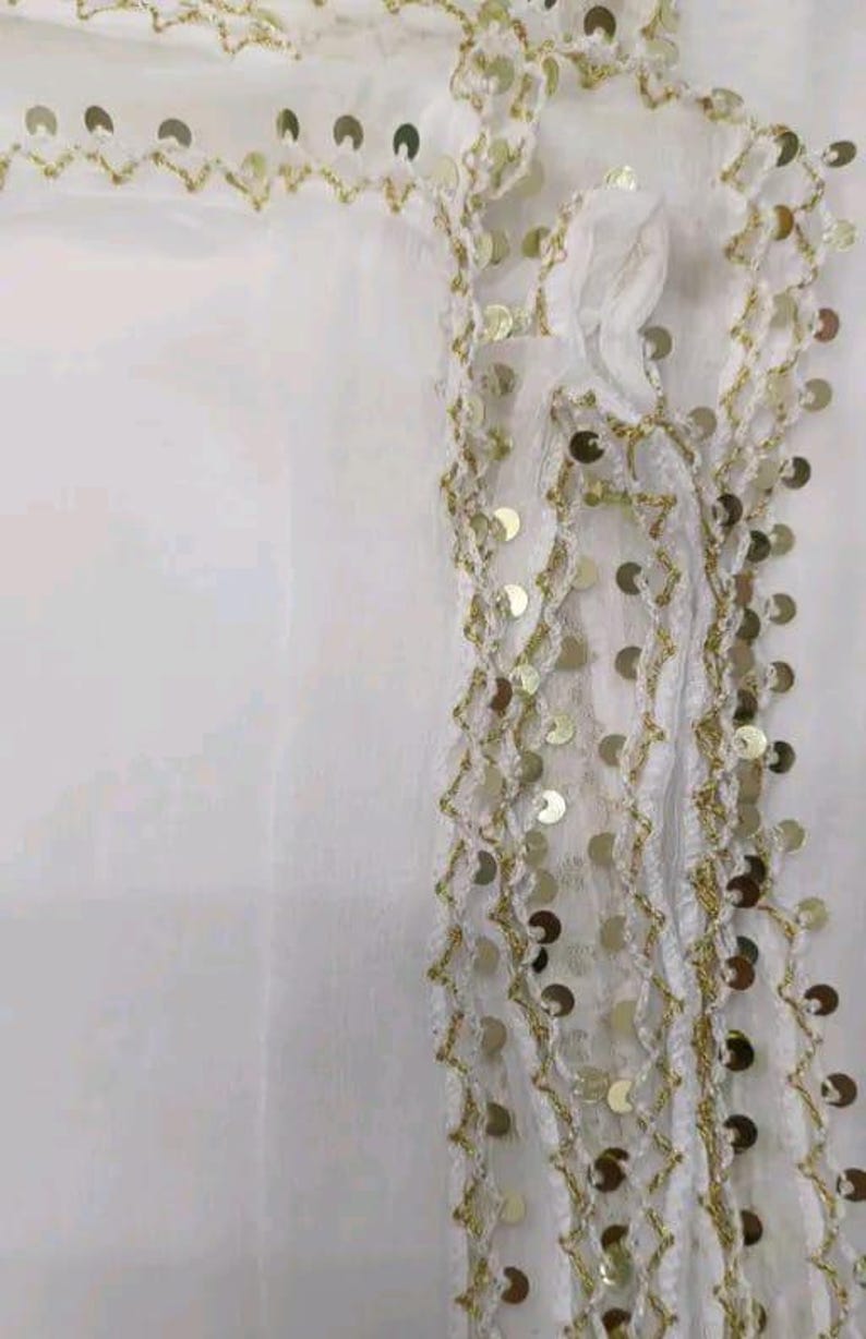 May include: White fabric with gold sequin and thread embellishments. The design features a zig-zag pattern with attached gold sequins. The fabric appears to be a sheer material, with the embellishments adding texture and visual interest.