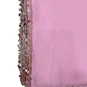 May include: A light pink fabric with a decorative border of silver sequins and gold thread. The fabric is folded, showing the texture and sheen of the material. The sequins are round and closely spaced along the edge.