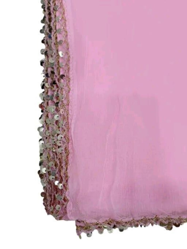 May include: A light pink fabric with a decorative border of silver sequins and gold thread. The fabric is folded, showing the texture and sheen of the material. The sequins are round and closely spaced along the edge.