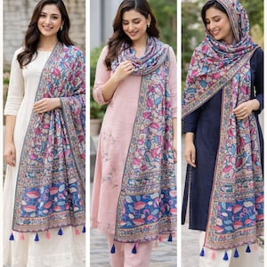 Puede incluir: Dupatta de algod&oacute;n y semi-lino con estampado Kalamkari. La imagen muestra a tres mujeres que llevan bufandas coloridas con un dise&ntilde;o floral en tonos azules, rosas y beige. Las bufandas tienen un borde con borlas. Las mujeres llevan diferentes atuendos.