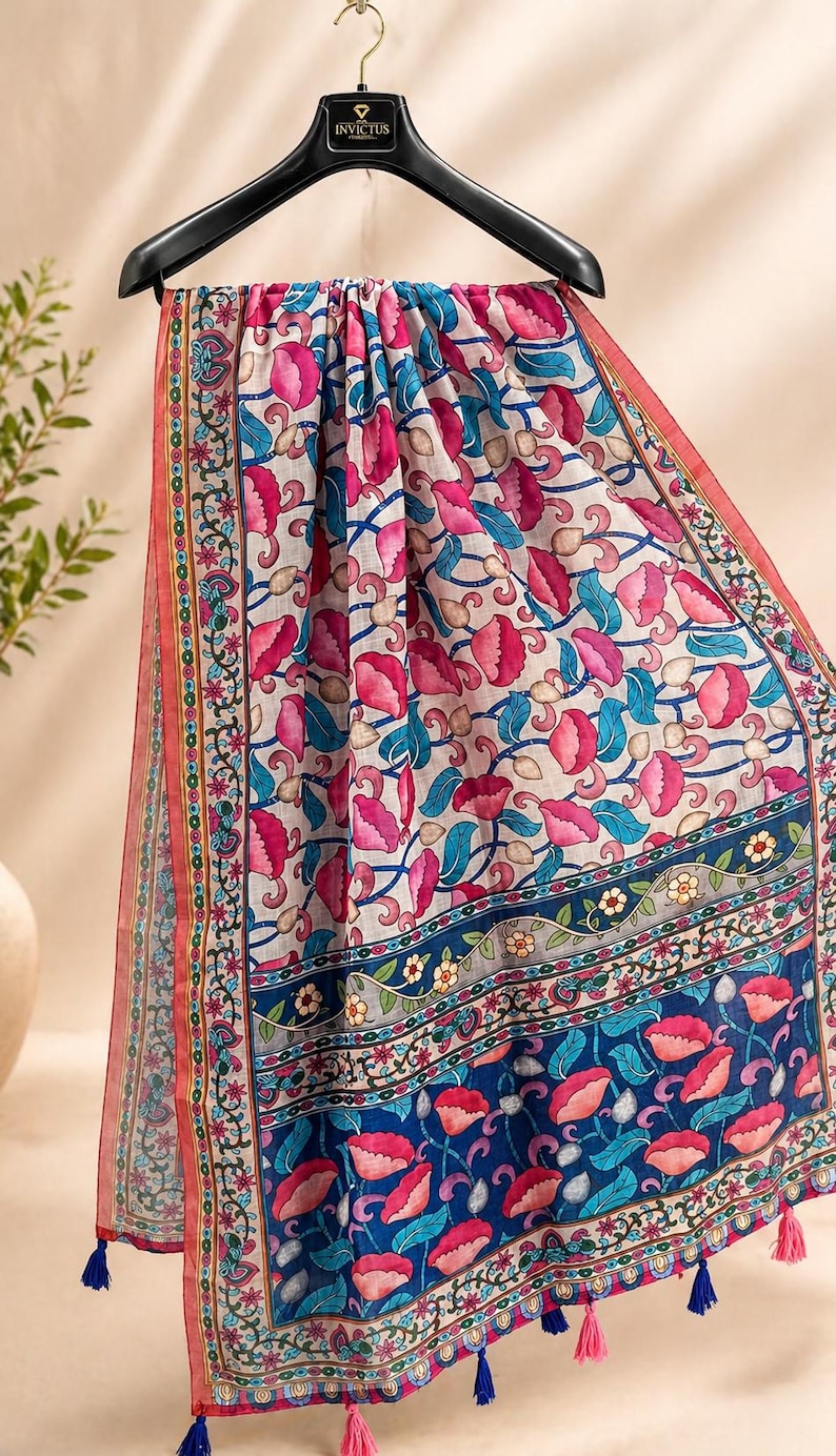 Puede incluir: Bufanda estampada con motivos florales en rosa, azul y blanco. La bufanda presenta un dise&ntilde;o repetitivo de flores rosas y hojas azules sobre un fondo blanco. Los bordes est&aacute;n adornados con un borde decorativo y borlas.
