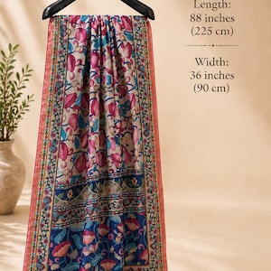 Puede incluir: Bufanda decorativa con estampado floral en tonos rosa, azul y beige, colgada de una percha negra. La bufanda mide 225 cm de largo y 90 cm de ancho, con borlas. El texto indica las dimensiones.
